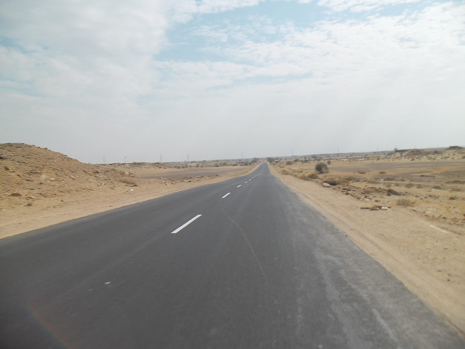 Straight desert highway running west from Jaisalmer towards the frontier
